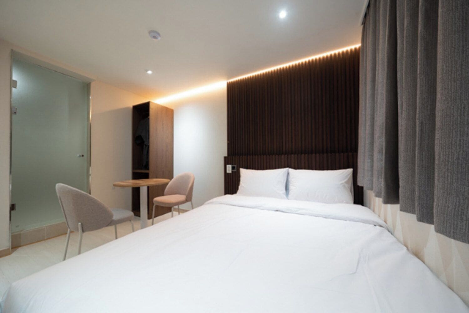Una habitación de hotel moderna con una cama grande, un escritorio y una silla.