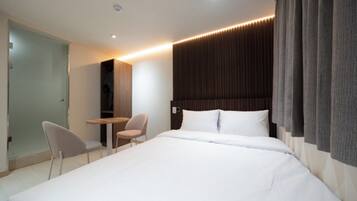 Una habitación de hotel moderna con una cama grande, un escritorio y una silla.