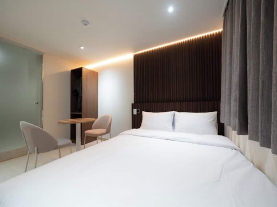 A modern hotel room with a large bed, a desk, and a chair.