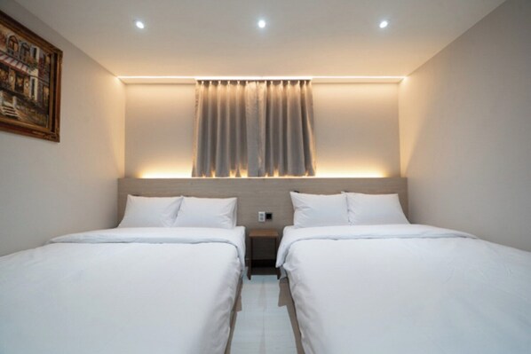 Habitación de hotel con dos camas, un cuadro en la pared y una ventana con cortinas.