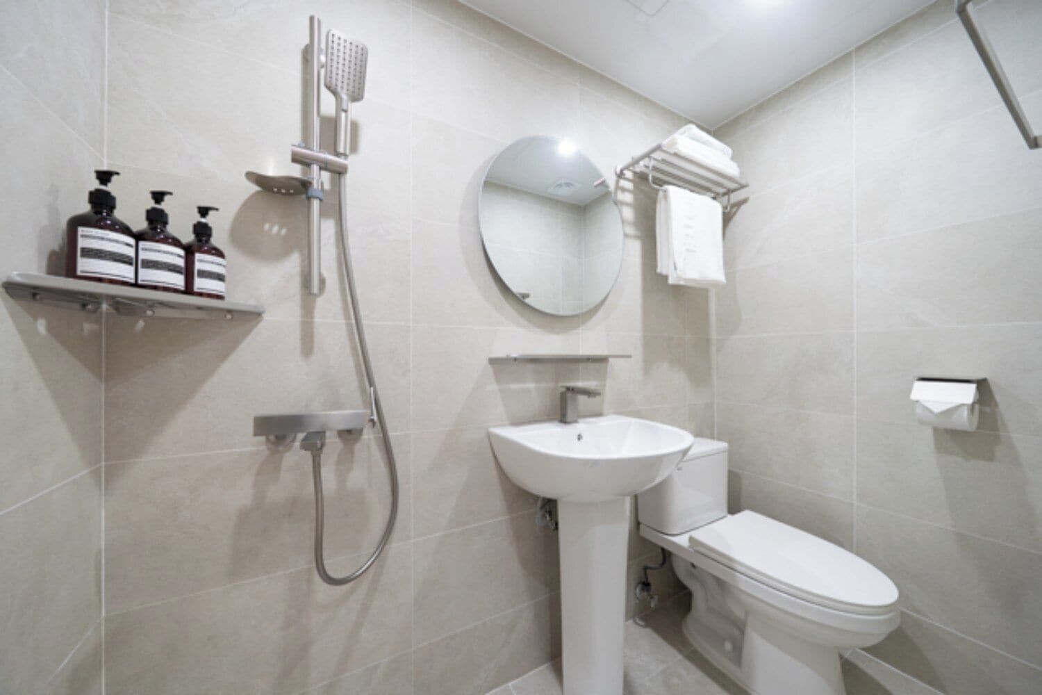 A modern bathroom with a shower, sink, toilet, and a towel rack.