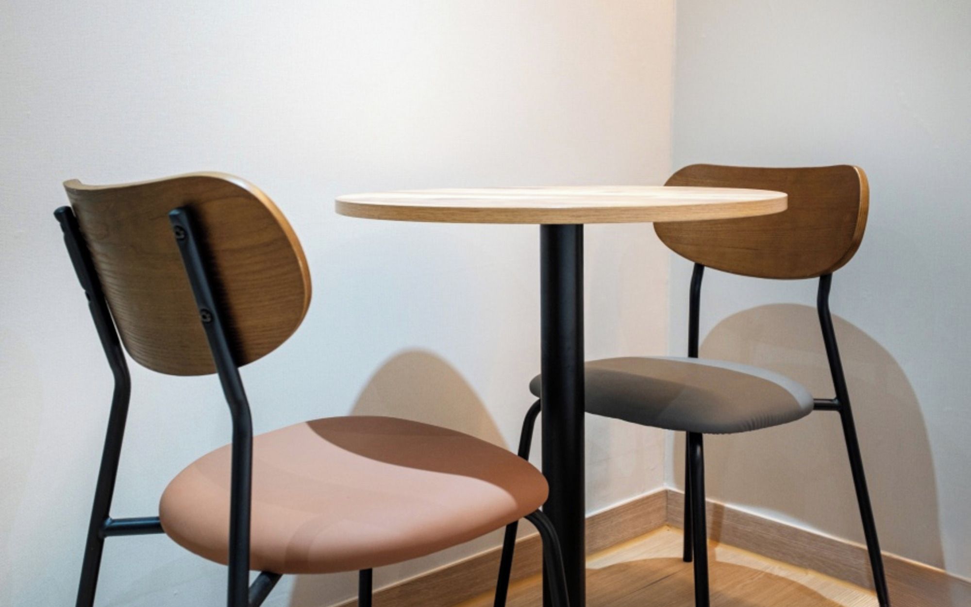 A corner of a room with two chairs and a small round table.