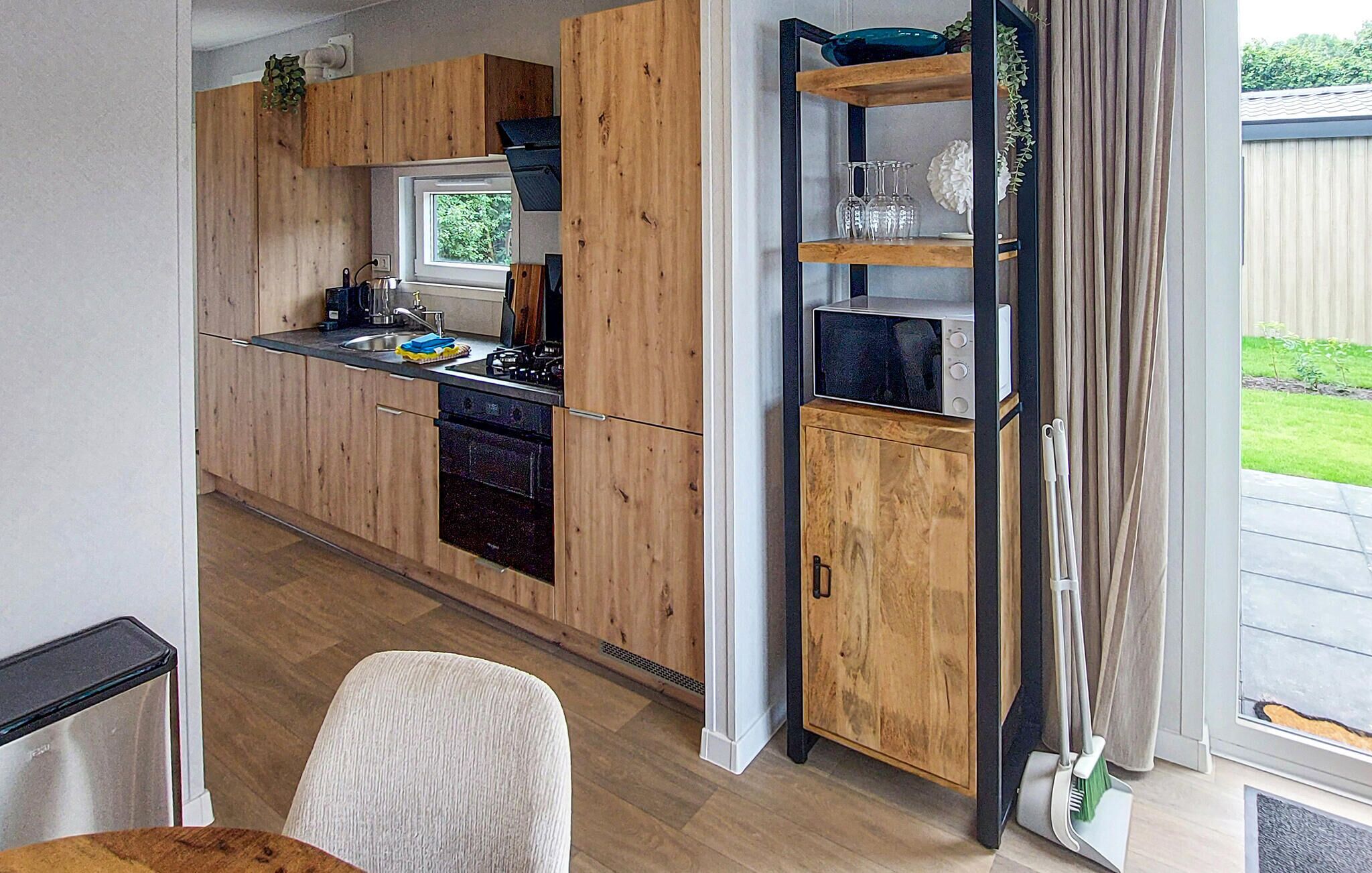 Une cuisine moderne avec des meubles en bois, un four encastré et une fenêtre.