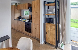 Eine moderne Küche mit Holzschränken, einem eingebauten Ofen und einem Fenster.