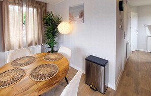 A dining area with a wooden table, woven placemats, chairs, a potted plant, and a wall-mounted lamp. - Nice home in Oude Pekela with WiFi (Oude Pekela)