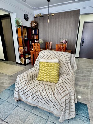 Ein modernes Wohnzimmer mit einer Couch, einer Wanddekoration, einem Bücherregal und einer Tür.