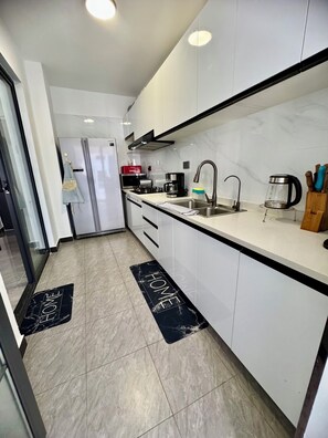 A modern kitchen with white cabinets, a stainless steel sink, a coffee maker, and a bread maker. - Zen On14, cozy 2bedroom in Lavington (Nairobi)