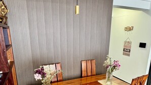 A dining area with a wooden table and chairs, a decorative wall, and a hanging light fixture. - Zen On14, cozy 2bedroom in Lavington (Nairobi)