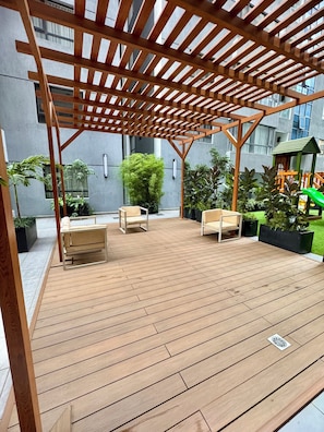 Eine Holzterrasse mit Sitzgelegenheiten im Freien und einer Pergola.