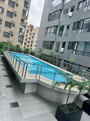 A residential building with a swimming pool, surrounded by potted plants and a tiled walkway. - Zen On14, cozy 2bedroom in Lavington (Nairobi)