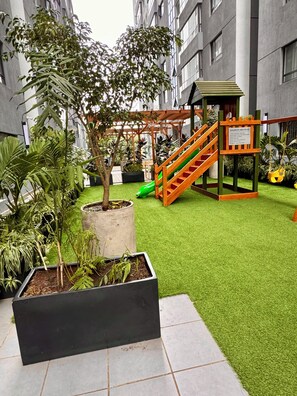 An outdoor play area with artificial grass, a wooden slide, and a climbing structure. - Zen On14, cozy 2bedroom in Lavington (Nairobi)