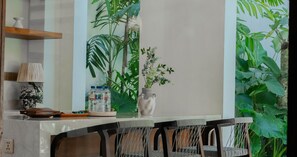 A modern kitchen with a bar area, featuring a large window with a view of tropical plants. - Uma Mimpi by Navya (Badung)