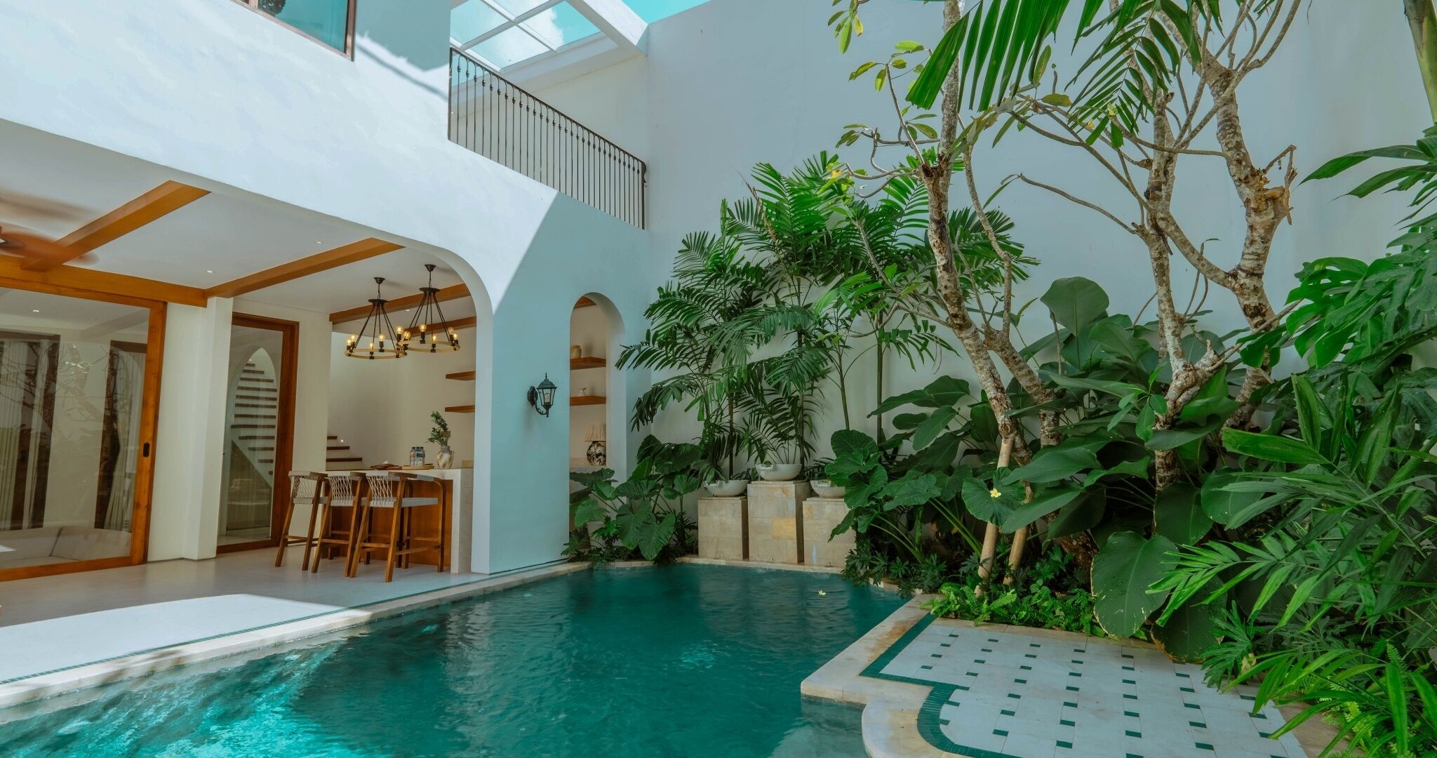 Un área de piscina interior moderna con comedor y una escalera que conduce a un nivel superior.