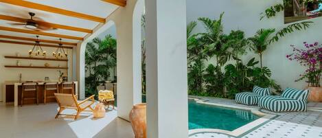 Un interior moderno con cocina, comedor y un área de descanso junto a la piscina.