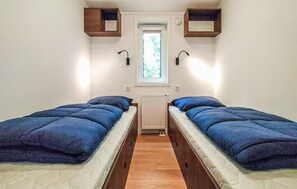 Habitación pequeña con dos camas, una ventana y un radiador.