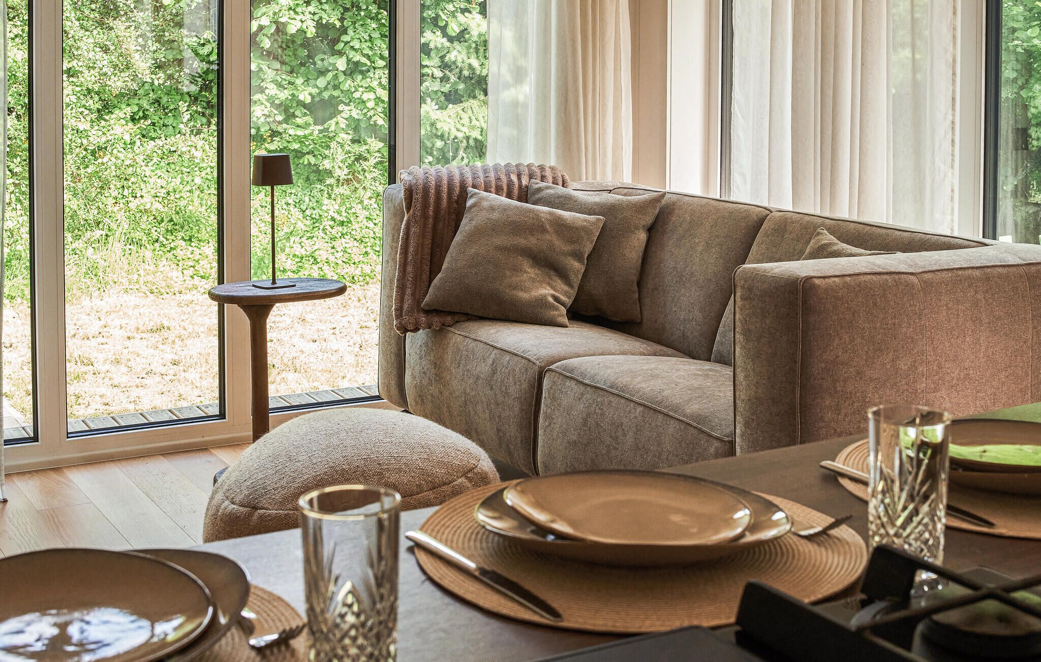 A cozy living room with a sofa, a small side table, and a dining area with plates and cutlery.