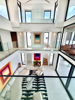 A modern interior with a central seating area, a staircase, and large windows.