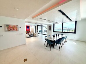 A spacious modern living area with a dining table, seating, and artwork on the walls.