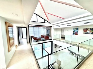 Ein modernes Interieur mit Glasgeländer, einer Sitzecke und Kunstwerken an den Wänden.