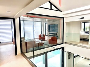 A modern interior with a glass railing, a sofa, and a television mounted on the wall.