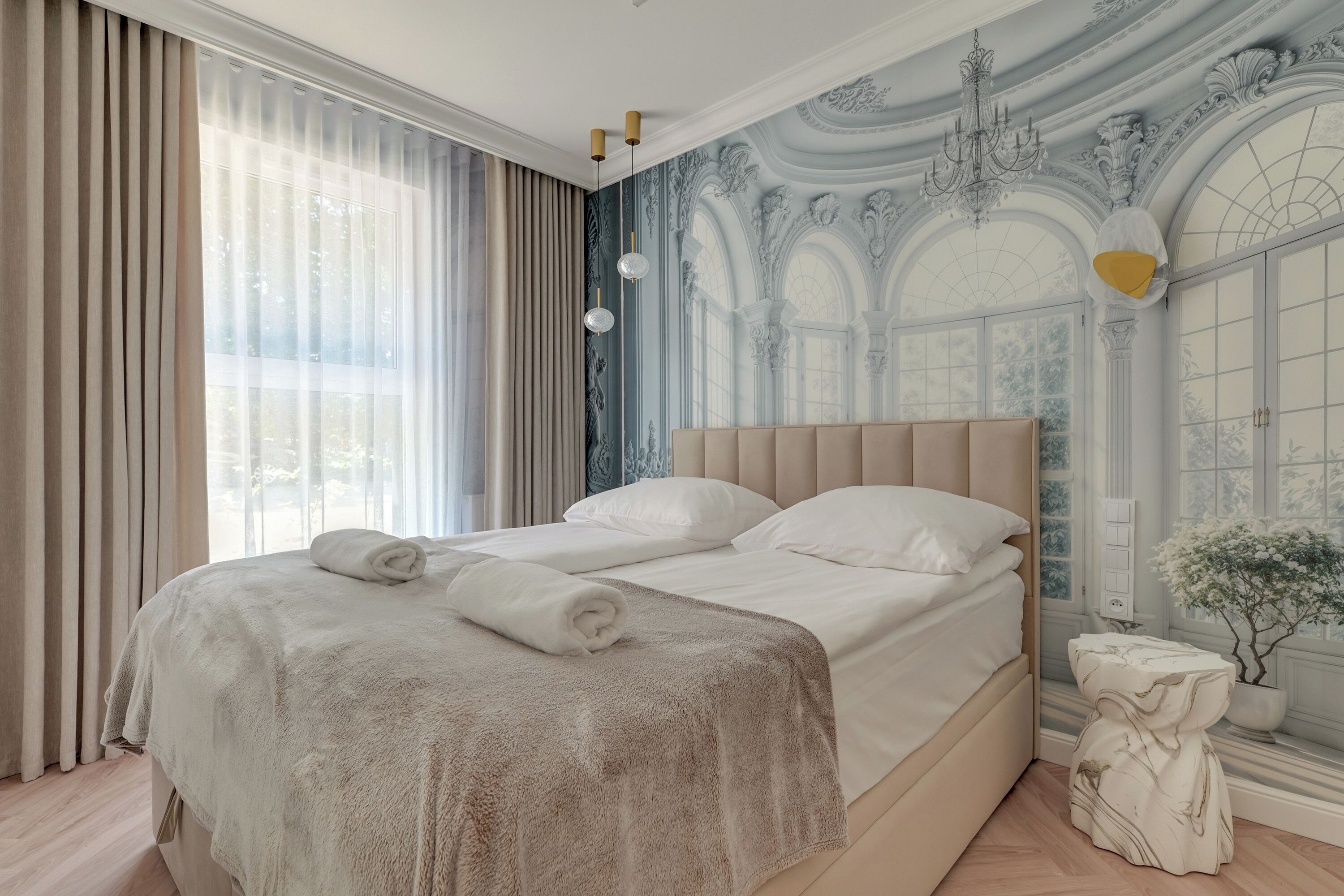 Habitació d'hotel amb un llit gran, una làmpada de cristall i una paret decorativa.