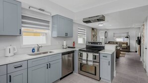 Eine moderne Küche mit grauen Schränken, Edelstahlgeräten und einem Essbereich mit einer Couch.
