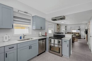 Una cocina moderna con gabinetes grises, electrodomésticos de acero inoxidable y una zona de comedor con un sofá.