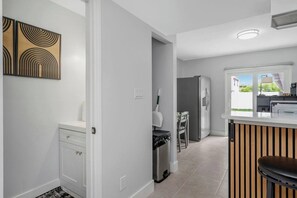 Una cocina moderna con refrigerador integrado, un comedor con mesa y sillas, y vistas al exterior.