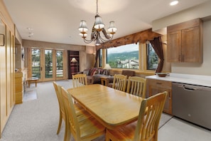 A spacious kitchen with a dining area, large windows, and a view of the mountains. - Ski-in/ski-out! Big Sky Resort! Community Pool/Hot Tub! (Big Sky)