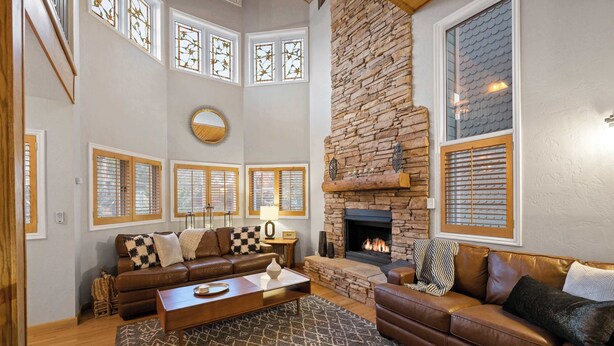 A spacious living room with a stone fireplace, leather sofas, and a large window with stained glass. - Old Town 3BR | Steps to Town Lift & Main St (Park City)