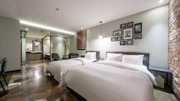 Habitación de hotel con una cama grande, un escritorio, una silla, un espejo y una pared de ladrillo.