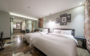 A hotel room with a large bed, a desk, a chair, a mirror, and a brick wall. - Yeoksam Premier Hotel YXM  (Seoul)