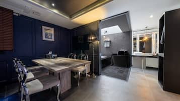 Un interior moderno con zona de comedor que incluye una mesa y sillas de madera, cocina con microondas y baño con ducha.