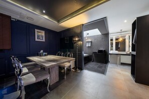 Un interior moderno con zona de comedor que incluye una mesa y sillas de madera, cocina con microondas y baño con ducha.