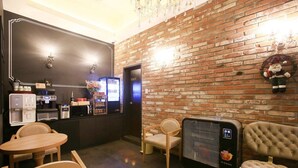 Un interior moderno con pared de ladrillo, cafetera, refrigerador y zona de estar.