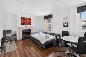 Ein modernes Schlafzimmer mit Bett, Kamin, Esstisch und Blick auf die Stadt.