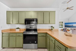 Eine Küche mit grünen Schränken, einem Edelstahlbackofen und einer Holz Arbeitsplatte.