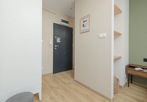 A hallway with a dark door, a wall-mounted air conditioner, a framed notice, and a small desk with a basket. - Szczecin Classy City Studio (Szczecin)