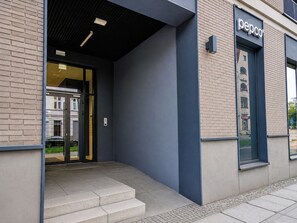 Entrada de un edificio con puerta de vidrio, un letrero que dice 'pepo' y una escalera que lleva a la entrada.