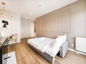 Un dormitorio moderno con una cama grande, un escritorio con silla y un armario.