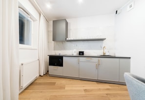A modern kitchen with grey cabinets, a black dishwasher, and a marble backsplash. - Sikorskiego Serene Apartment (Poznań)