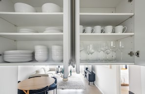 A modern kitchen with white cabinetry, a dining area with a round table, and a built-in wine rack. - Blueground | Manhattan, rooftop, nr Empire State (New York)
