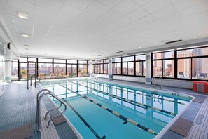 An indoor swimming pool with clear lanes, large windows, and a city view. - Blueground | Manhattan, rooftop, nr Empire State (New York)