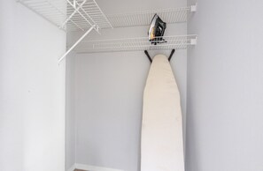 A room with a white ironing board, a ceiling-mounted ironing board rail, and a ceiling fan. - Blueground | Manhattan, rooftop, nr Empire State (New York)