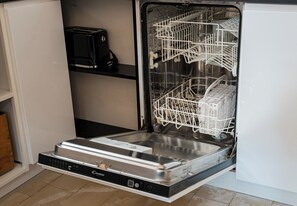 An open dishwasher with a control panel and a metal rack inside. - Old Town Heritage Apartment (Warszawa)