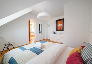 Une chambre à coucher avec un lit, une chaise, une commode et un tableau au mur.
