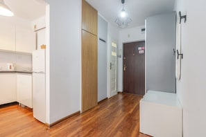 Eine moderne Küche mit weißen Schränken, einer Holztür und einer weißen Arbeitsplatte.
