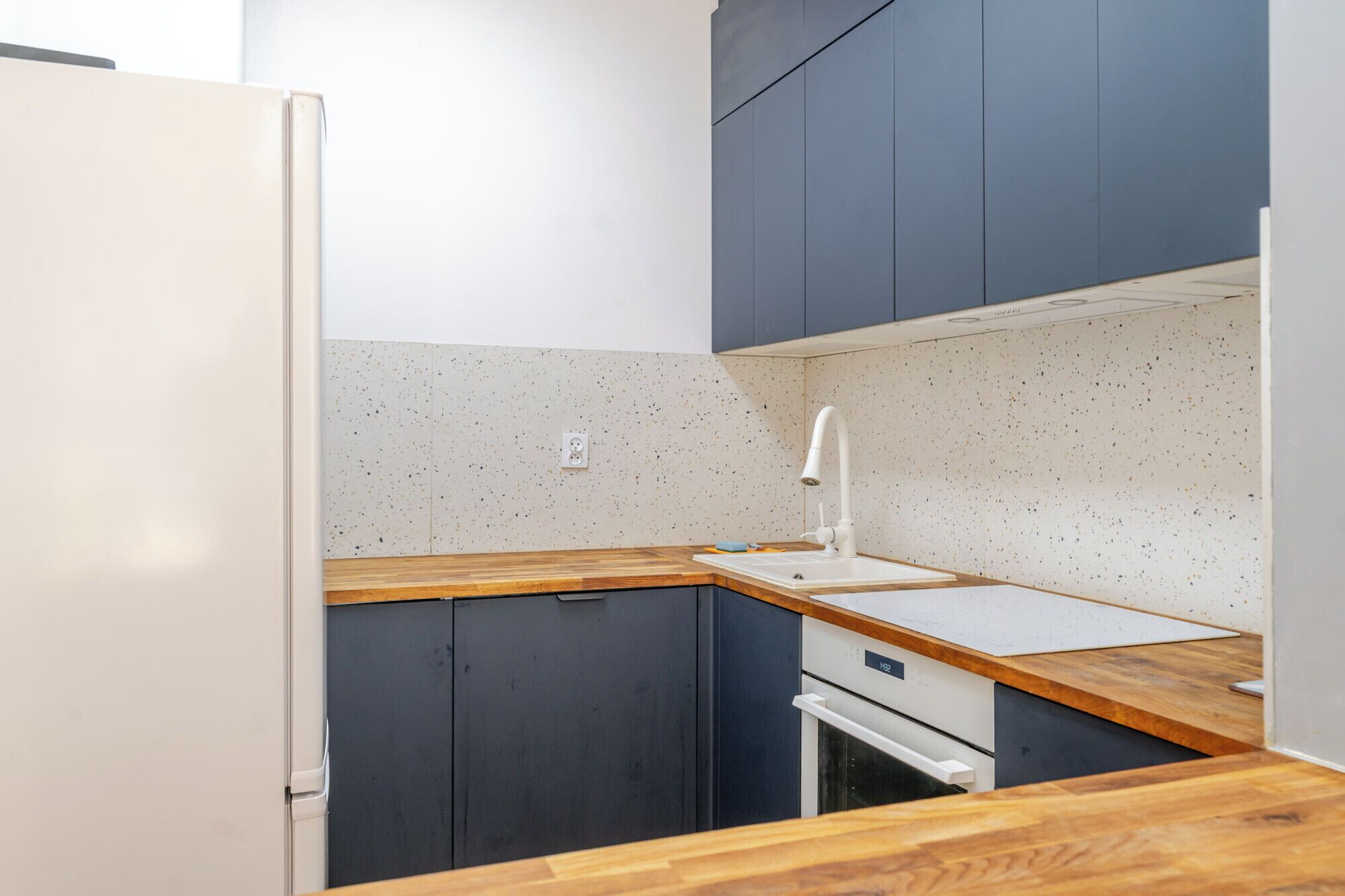 A compact kitchen with dark cabinets, a white countertop, and a built-in oven.