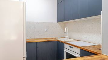 A compact kitchen with dark cabinets, a white countertop, and a built-in oven.