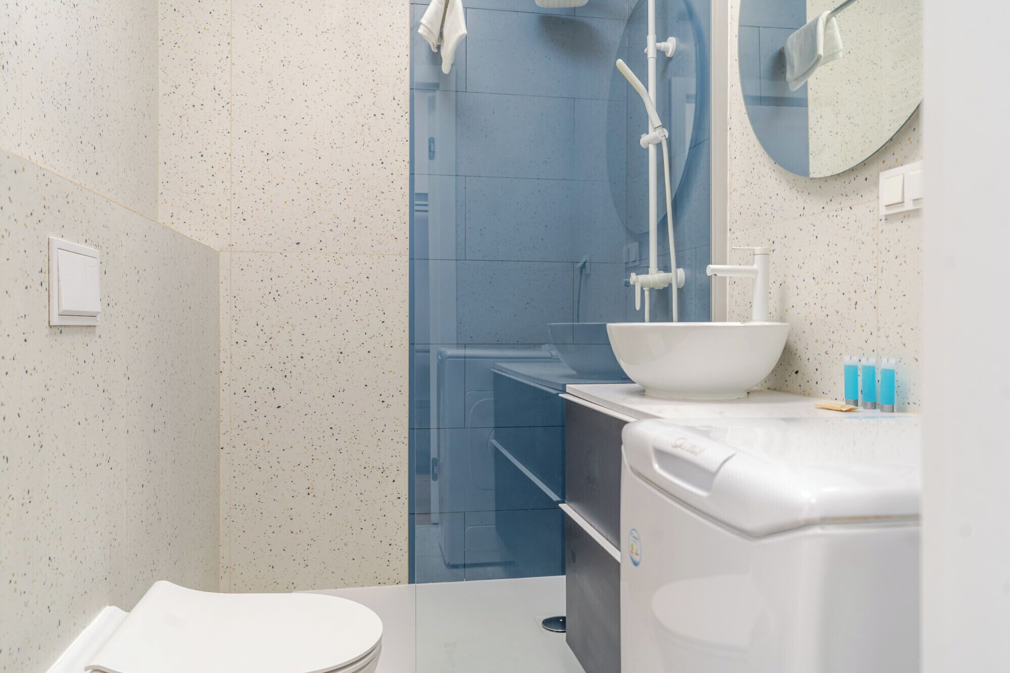 A bathroom with a white toilet, a white sink, and a glass shower enclosure.